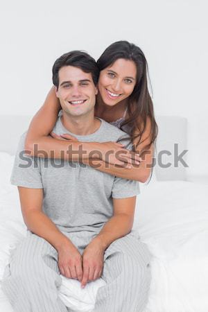 Stock photo: Smiling couple using a laptop sitting on a bed