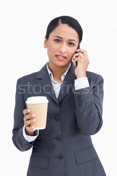 Close up of serious saleswoman with paper cup and cellphone against a white background Stock photo © wavebreak_media