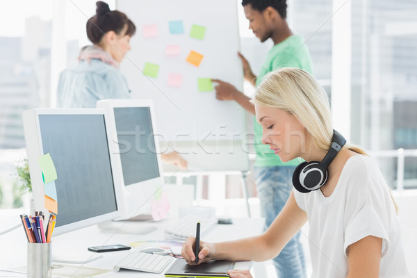 Stock photo: Artist drawing something on graphic tablet with colleagues behin