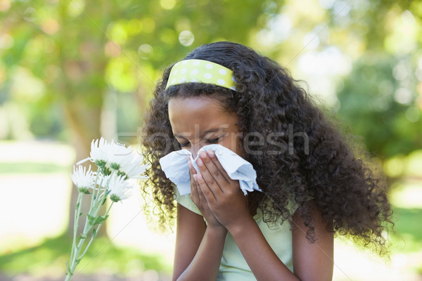 Young girl sitting by flower and blowing her nose in the park Stock photo © wavebreak_media
