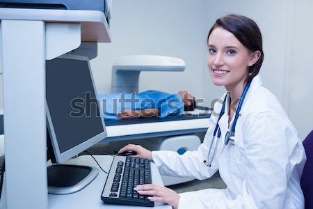 Stock photo: Doctor looking her computer while proceeding a radiography