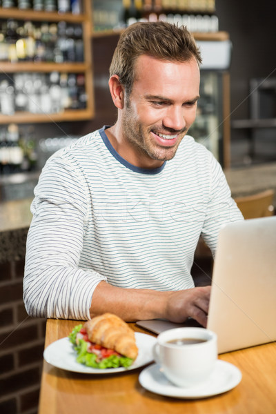 Hombre guapo usando la computadora portátil croissant pub ordenador hombre Foto stock © wavebreak_media