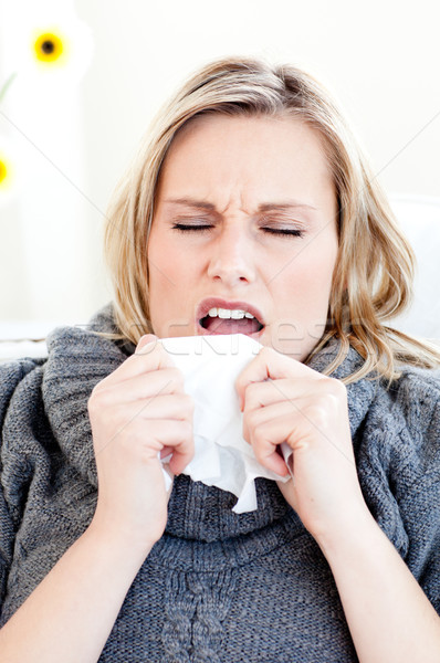 Diseased woman sneezing holding a tissue in the living-room Stock photo © wavebreak_media