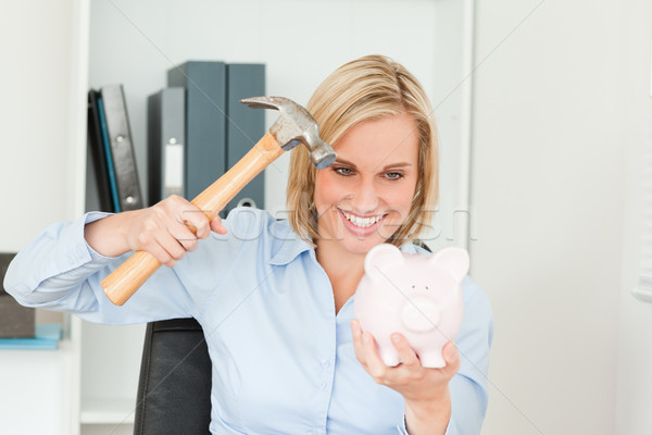 Smiling blonde woman wanting to destroy her piggy bank in her office Stock photo © wavebreak_media