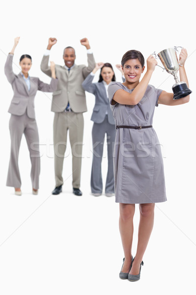 Picture centered on woman smiling and holding up a cup with co-workers raising their arms in the bac Stock photo © wavebreak_media