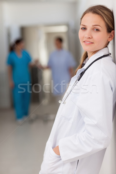 Smiling doctor standing against a wall with her hands in her pockets in a hallway Stock photo © wavebreak_media