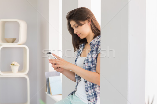Pretty brunette sitting beside her window sending a text Stock photo © wavebreak_media