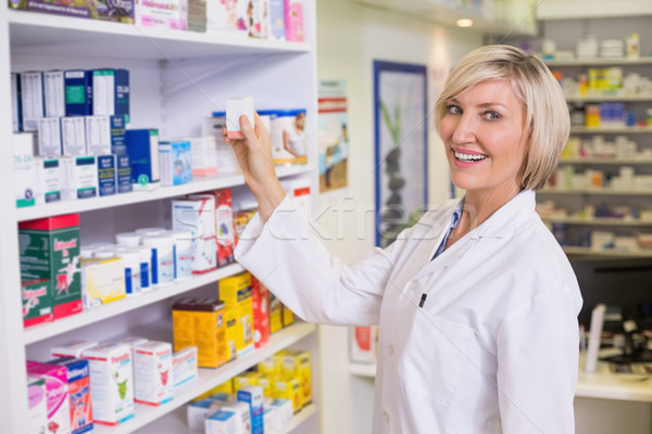 Stock photo: Junior pharmacist taking medicine from shelf