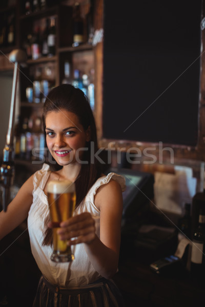 Female bar tender holding glass of beer Stock photo © wavebreak_media