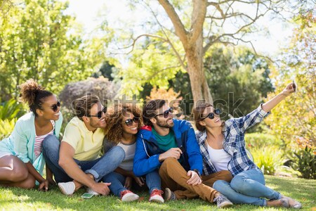 Stock photo: Friends enjoying while sitting on field during picnic