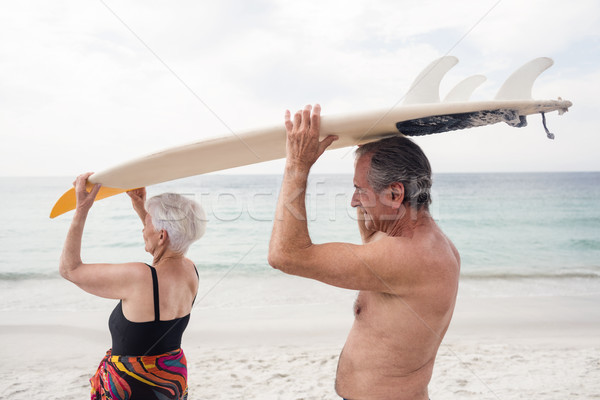 Senior couple carrying a surfboard over their head Stock photo © wavebreak_media