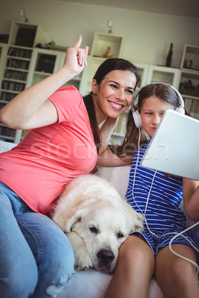 Happy mother and daughter sitting with pet dog and using digital Stock photo © wavebreak_media