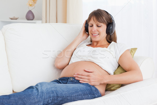 Smiling pregnant woman listening to music in her living room Stock photo © wavebreak_media