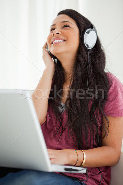 Close-up of a happy Latino student enjoying music with a laptop on her sofa Stock photo © wavebreak_media