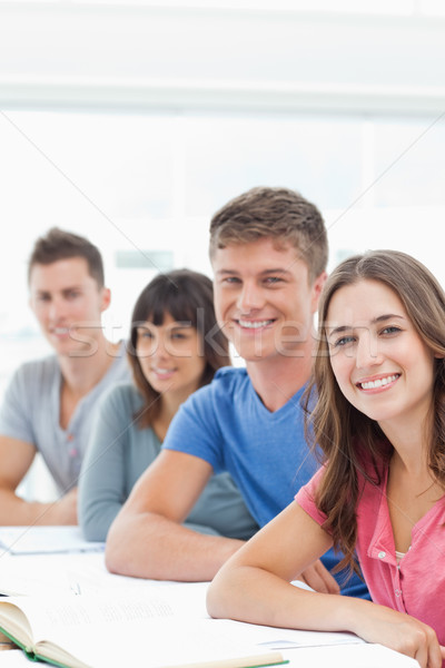 Stock photo: A smiling group of people looking into the camera and smiling with books in front of them 