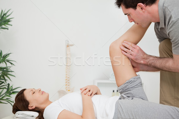 Serious physiotherapist raising a leg in a room Stock photo © wavebreak_media