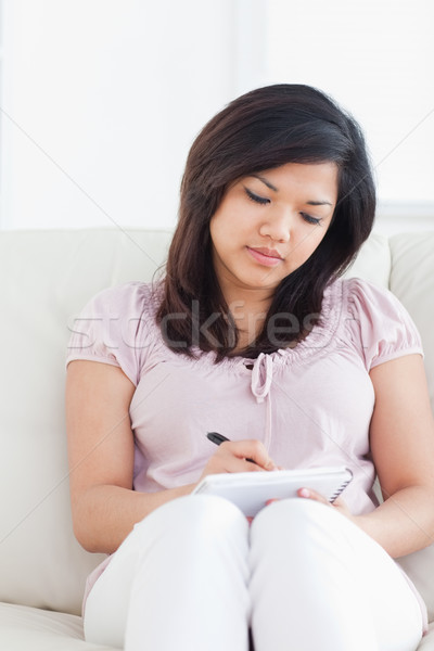Mujer sesión sofá escrito cuaderno salón Foto stock © wavebreak_media
