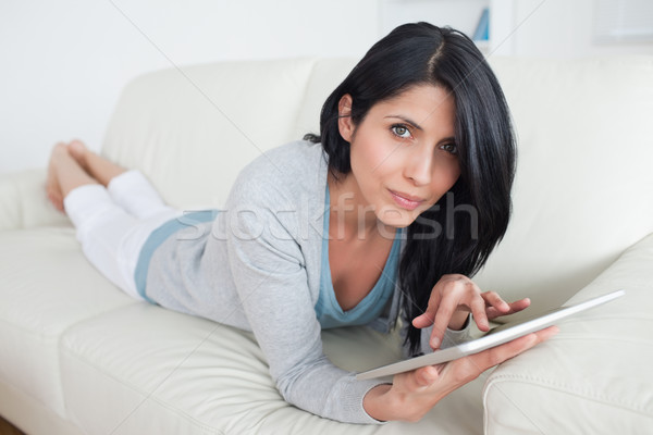 Woman resting on a sofa while touching a tactile tablet in a living room Stock photo © wavebreak_media