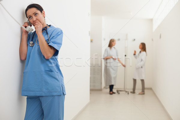 Nurse using payphone with doctor talking to patient in hallway Stock photo © wavebreak_media