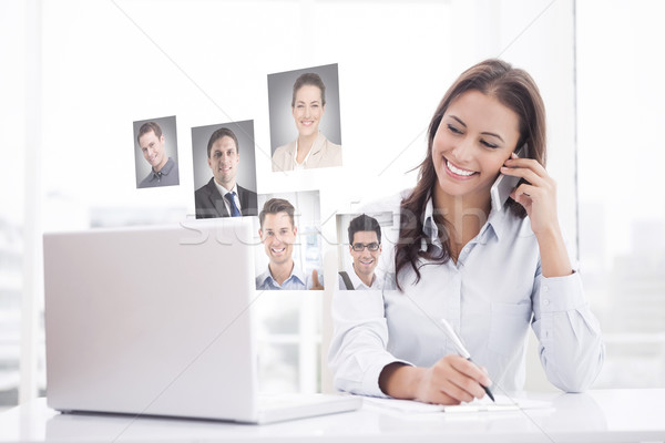 Composite image of happy businesswoman using laptop at her desk Stock photo © wavebreak_media