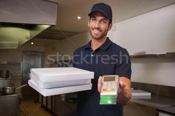 Cheerful pizza delivery man holding credit card machine Stock photo © wavebreak_media