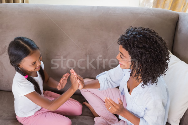 Pretty mother playing clapping game with daughter on couch Stock photo © wavebreak_media