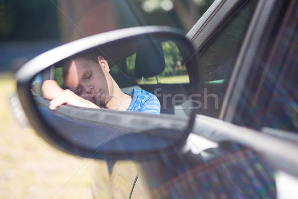 Reflection of teenage boy in wing mirror sleeping in car Stock photo © wavebreak_media