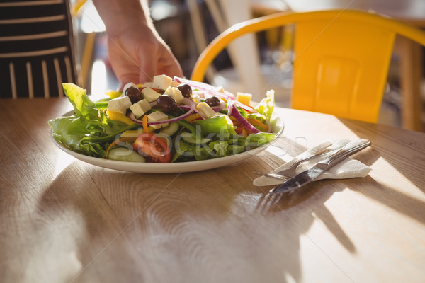 Stock photo: Cropped hand of waiter serving salad on table