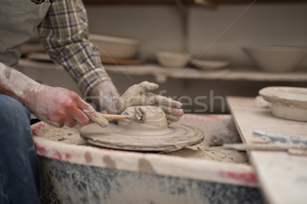 Stock photo: Mid section of male potter molding plate with hand tool