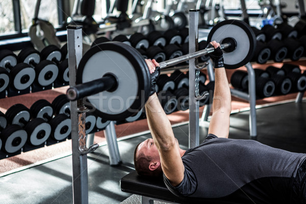 Muscular man lifting barebell while lying on bench Stock photo © wavebreak_media