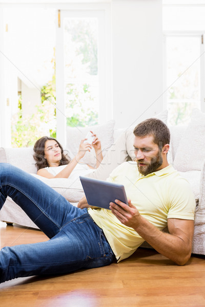 Couple using mobile phone and digital tablet in living room Stock photo © wavebreak_media