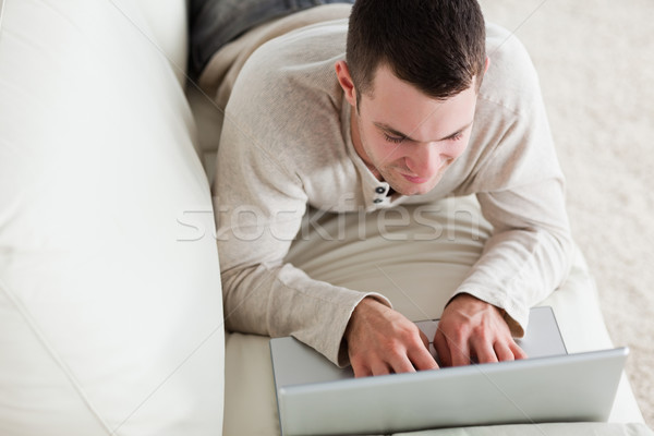 Jeune homme canapé portable salon ordinateur maison [[stock_photo]] © wavebreak_media