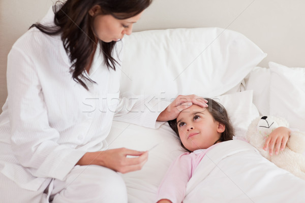 Stock photo: Mother checking on her daughter's temperature in a bedroom