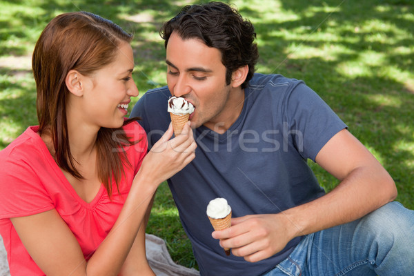 Smiling woman feeding her friend an ice cream cone as they sit next to each other on the grass Stock photo © wavebreak_media