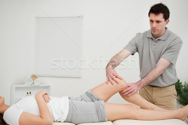 Serious doctor holding the knee of a woman in a room Stock photo © wavebreak_media