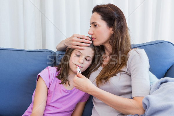 Mother taking temperature of sick daughter Stock photo © wavebreak_media
