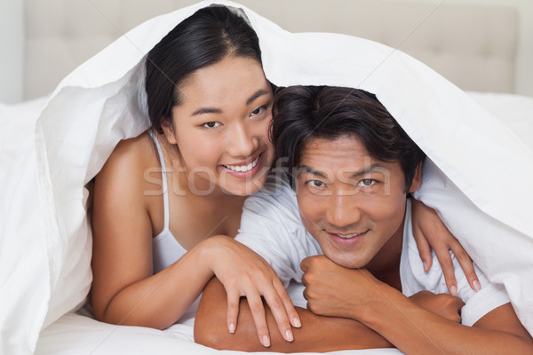 Happy couple lying on bed together under the duvet Stock photo © wavebreak_media