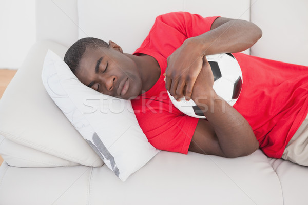 Football fan sleeping on couch hugging ball Stock photo © wavebreak_media