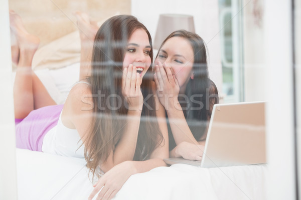 Pretty friends using laptop on bed Stock photo © wavebreak_media