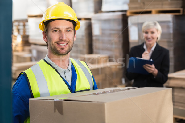 Warehouse worker holding box with manager behind him Stock photo © wavebreak_media