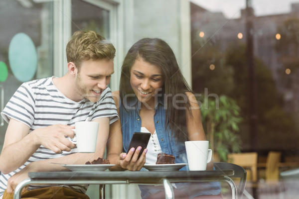 Stock photo: Smiling friends with chocolate cake using smartphone