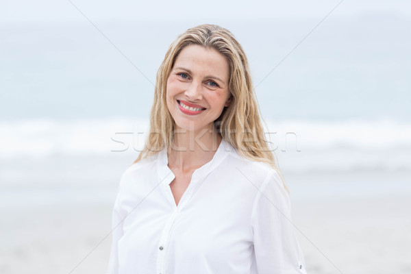 Smiling blonde standing by the sea and looking at camera Stock photo © wavebreak_media