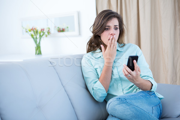 Surprised brunette looking at her smartphone  Stock photo © wavebreak_media