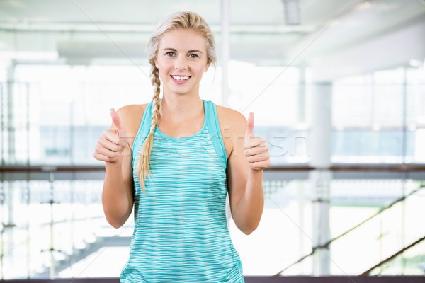 Smiling blonde standing and showing thumbs up Stock photo © wavebreak_media