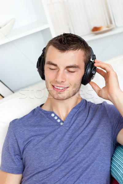 Młody człowiek słuchanie muzyki słuchawki domu uśmiech Zdjęcia stock © wavebreak_media