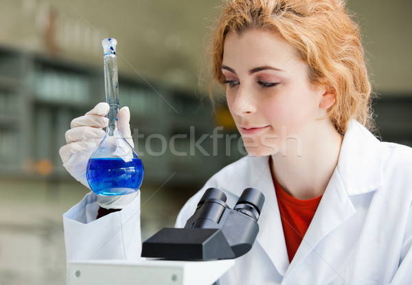 Smiling student looking at a blue liquidin a laboratory Stock photo © wavebreak_media
