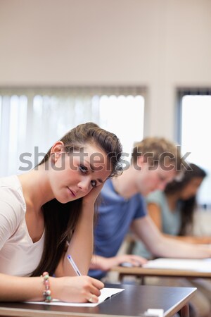 Young student raising his hand while his classmates are taking notes in an amphithater Stock photo © wavebreak_media