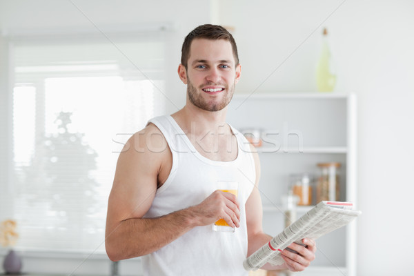 Handsome man drinking orange juice while reading the news in his kitchen Stock photo © wavebreak_media