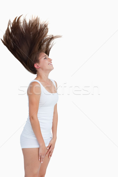 Stock photo: Smiling brunette flipping her hair against a white background