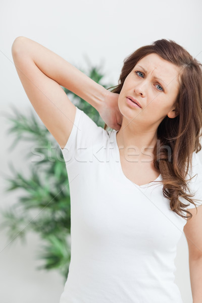 brunette standing while placing her hand on her neck in a room Stock photo © wavebreak_media